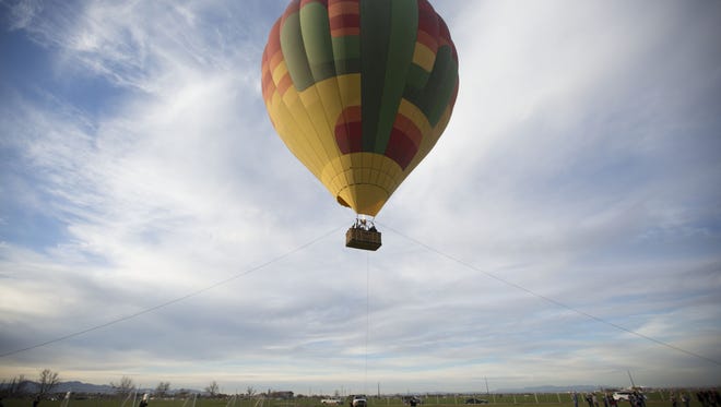 Captain Mike England takes passengers up on a tethered balloon ride during the Arizona Balloon Classic at the Fear Farm Sports and Entertainment Complex.
