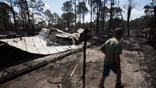 Lehigh Acres Steve Smith walks by his destroyed workshop on Monday morning. He lost thousands of dollars in tools, vehicles and property when a fire ravaged through his neighborhood on Sunday.  