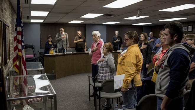 Attendees stand with their hands over their hearts as the Pledge of Allegiance is recited during a city council meeting Tuesday, Nov. 1, 2016, at Algonac City Hall.