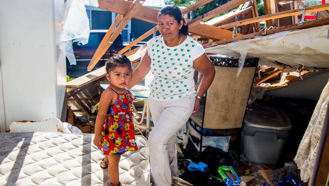 Eustolia Flores and her daughter Jocelyn, 1, stand in their trailer that was destroyed by Hurricane Irma in Immokalee on Wednesday, Sept. 13, 2017. Flores and her four children are staying in their neighbor's trailer with them for now. 