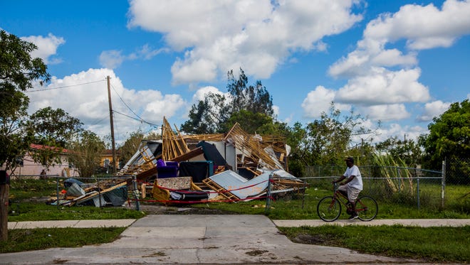A man rides his bike by a trailer that was destroyed by Hurricane Irma in Immokalee on Tuesday, Sept. 12, 2017. 