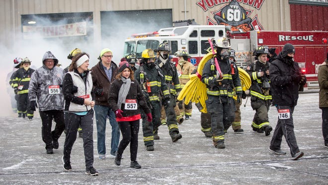 Members of the Yorktown Fire Department walk in full gear along with the participants of the Fire and Ice Holiday 5k on Dec. 9 in Yorktown. To help boost numbers, goals were set that determined how much gear Yorktown Fire Chief David Boone had to carry during the run.