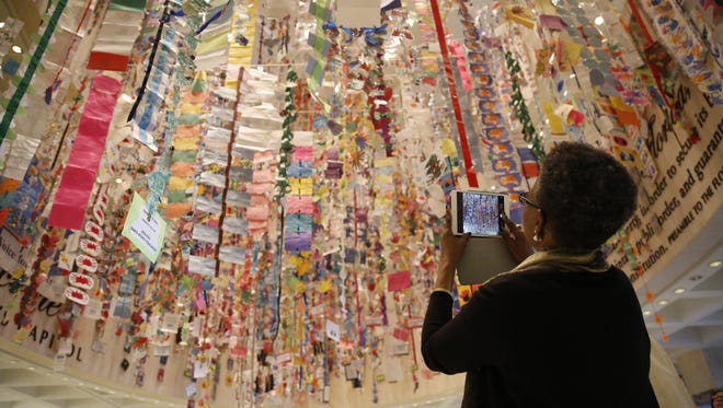 A Capitol visitor admires the artwork of children from across the state, which was strung up by volunteers during the annual Hanging of the Hands in the Capitol rotunda Sunday. The event kicks off this year's Children's Week at the Capitol.