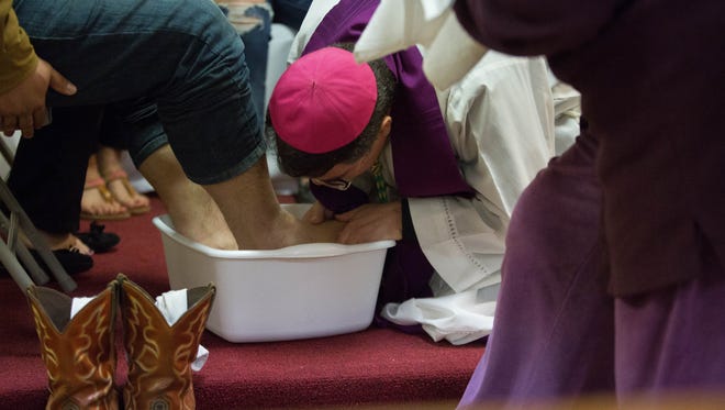 Bishop Oscar Cantú leans down to kiss the feet of a DREAMer before washing the feet of  other Deferred Action for Childhood Arrival recipients, during a ceremonial washing of the feet at the San Pedro Catholic Mission in Vado on Tuesday Feb 20, 2018
