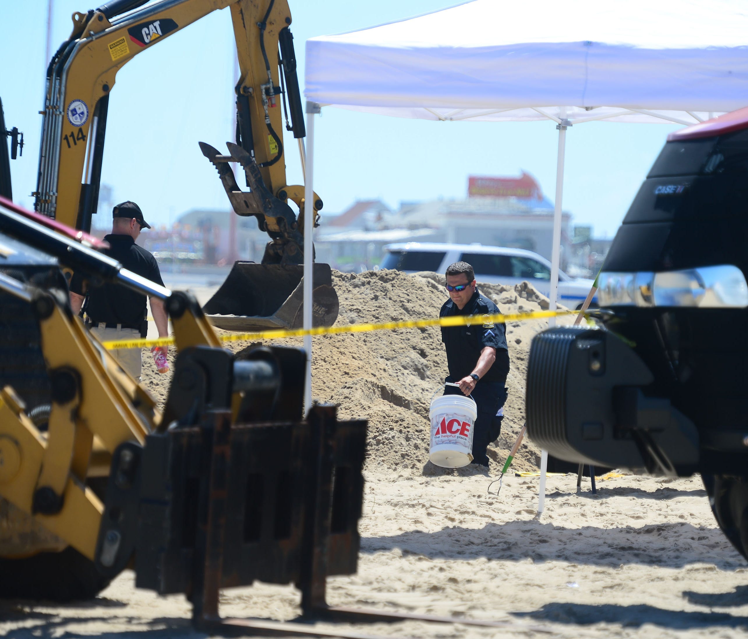 Ocean City Police carry out buckets of sand to be sifted  from a deep hole that was dug around the area where an unidentified body was found this morning around the 2nd Street beach in Ocean City, Md. on Monday, July 31, 2017.