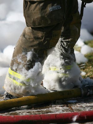 Foam covers the feet of a firefighter in Stanhope after he walked out from inside the house where the foam was being used to knock down the flames.