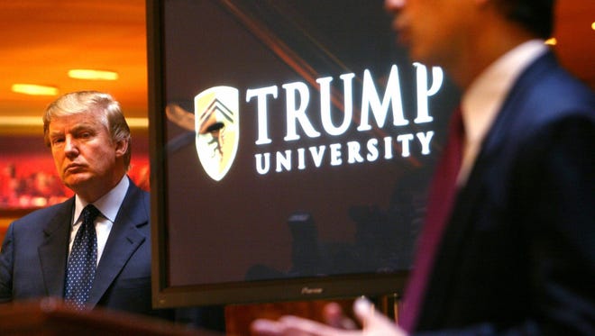 Donald Trump listens as Michael Sexton (R) introduces him to announce the establishment of Trump University at a press conference in New York.