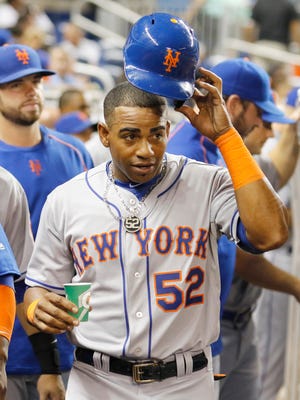 New York Mets outfielder Yoenis Cespedes walks in the dugout after he scored on a double by teammate Wilmer Flores in the fifth inning against the Miami Marlins  on Monday Aug. 3, 2015.