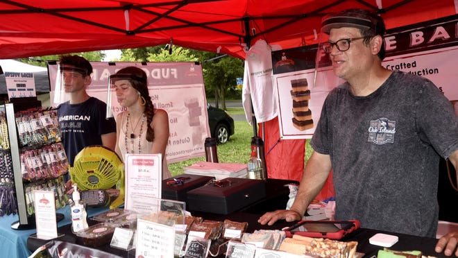 "Your Chocolate Guys" owner Mike Galanti wears a face shield as he sells his products at the New Britain Farmers Market Wednesday afternoon. Galanti's son Joshua, left, and Felicity Mangeri also wear face shields as they sell their own product, Spiffy Laces.