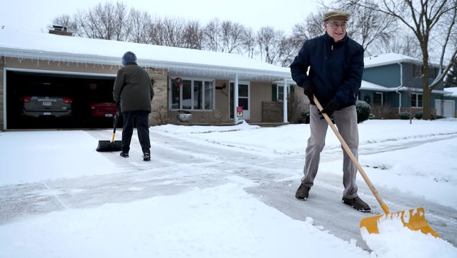 Michael Schmelzer and his wife, Ruth, of Appleton, shovel a path in their driveway before heading to church Friday, Dec. 22, 2017, in Appleton, Wis.