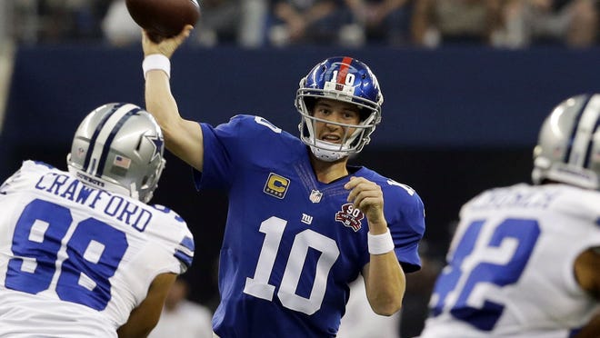 
New York Giants quarterback Eli Manning (10) passes between Dallas Cowboys defensive end Tyrone Crawford (98) and free safety Barry Church (42) during the first half of an NFL football game, Sunday, Oct. 19, 2014, in Arlington, Texas. 

