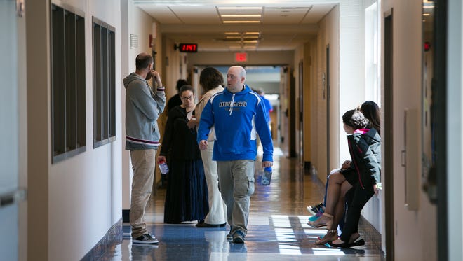 Staff members walk the hallway of Howard High School of Technology where a 15-year-old student died after she was assaulted Thursday morning.