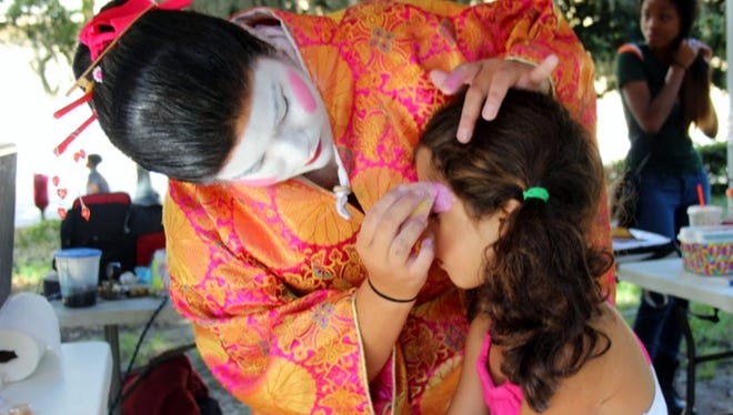 A child gets her face painted in traditional Japanese performance makeup