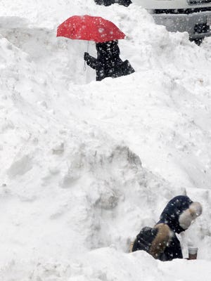 Commuters walk between piles of snow on a street in downtown Boston on Feb. 11, 2015.