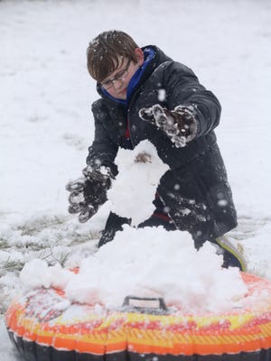 Jonathan Keith, 11, packs snow on an inflatable sled to guild a giant snowball to toss outside his Murfreesboro home on Friday, Jan. 22, 2016, as snow continues to fall.