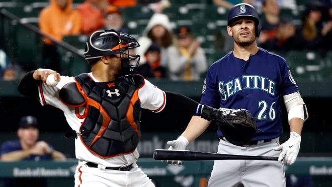 Seattle Mariners' Danny Valencia (right) walks off the field after striking out swinging next to Baltimore Orioles catcher Welington Castillo during the second inning of Tuesday's game.