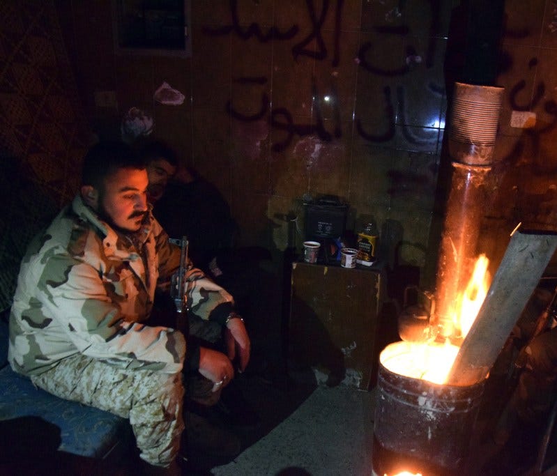 Syrian government troops sit around a fire in Aleppo, Syria, on Dec. 29.