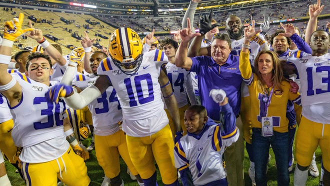 LSU coach Ed Orgeron; his wife, Kelly; and players celebrate the team's 56-20 victory over Arkansas in an NCAA college football game in Baton Rouge, La., Saturday, Nov. 23, 2019. (AP Photo/Matthew Hinton)