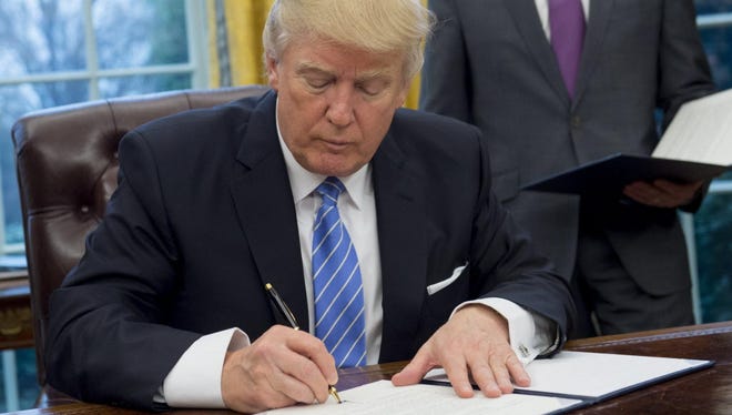 President Donald Trump signs an executive order withdrawing the U.S. from the Trans-Pacific Partnership in the Oval Office on Jan. 23, 2017.