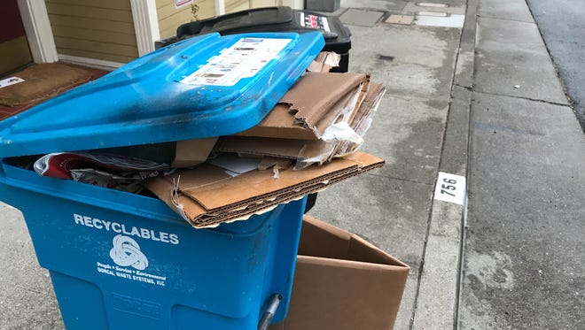 A recycling bin overflows with corrugated cardboard boxes.