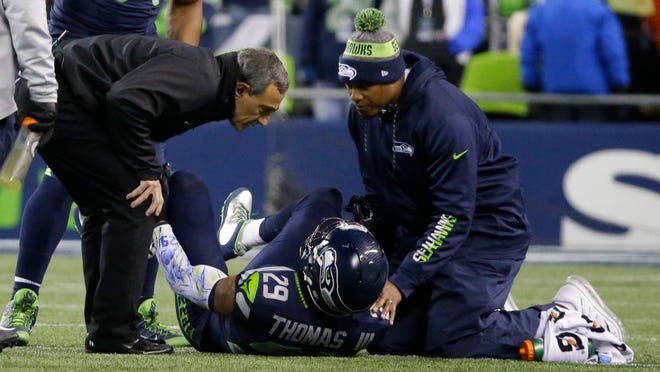 Seattle Seahawks free safety Earl Thomas (29) is examined by team physician Dr. Ed Khalfayan, left, after going down with an injury in the first half of an NFL football game against the Carolina Panthers, Sunday, Dec. 4, 2016, in Seattle. (AP Photo/Ted S. Warren)