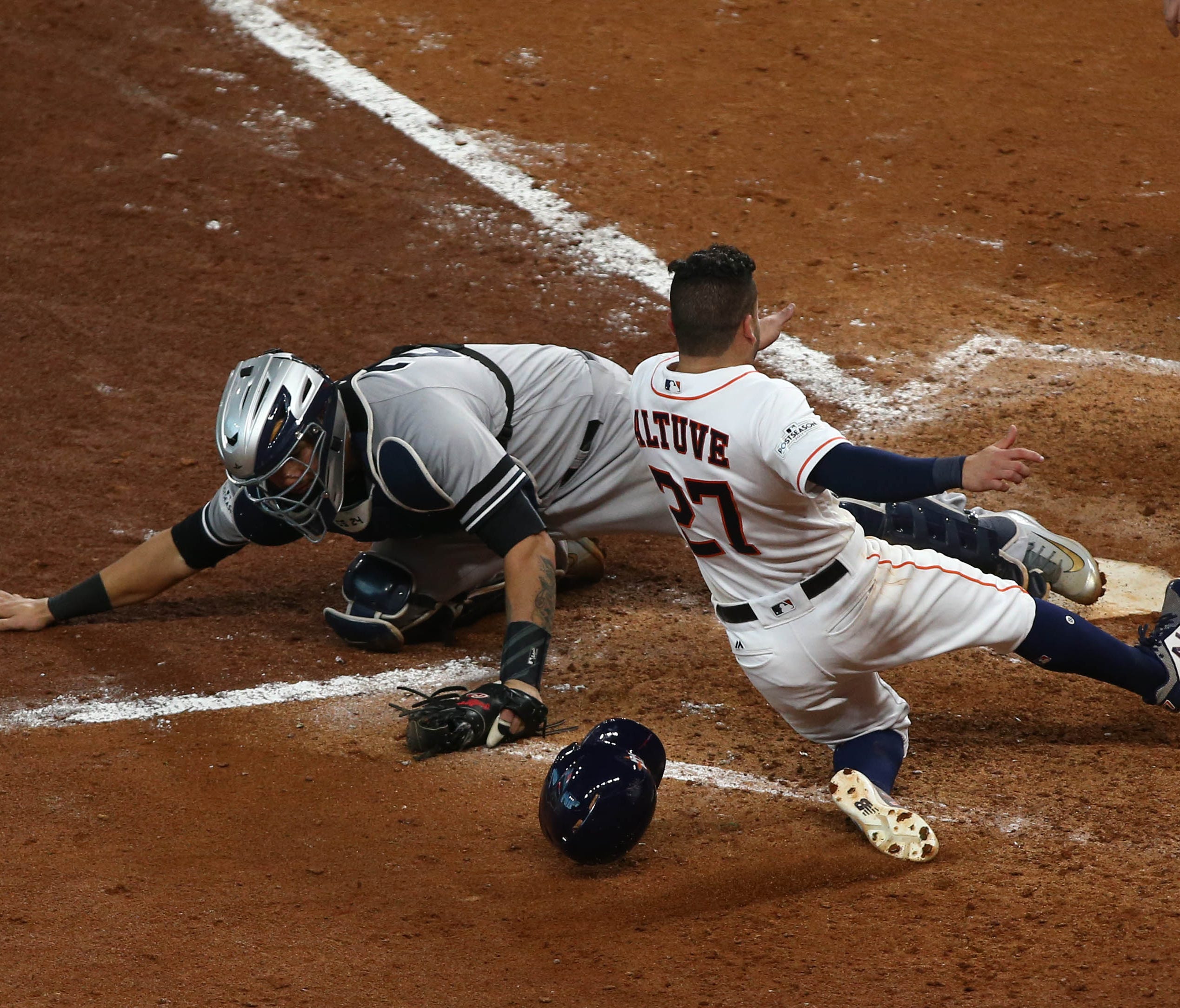 Oct 14, 2017; Houston, TX, USA; Houston Astros second baseman Jose Altuve (27) crosses home plate for the winning run as New York Yankees catcher Gary Sanchez (24) reaches for the ball during the ninth inning in game two of the 2017 ALCS playoff base