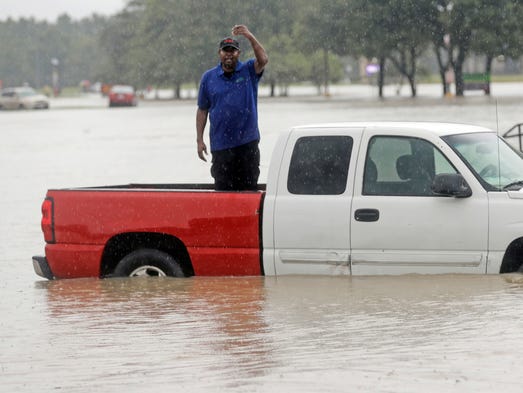 A man waves for help as he is surrounded by floodwaters