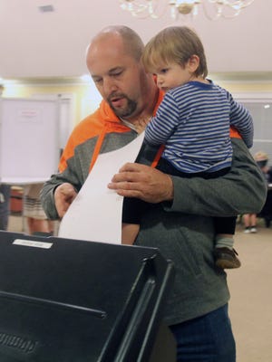 Rob Fox, holds his son Zachary as he casts his ballot at the Southeast Town Hall Nov. 8, 2016.