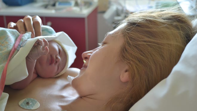 The first moments of mother and newborn after childbirth. Mother holding her newborn baby child after labor in a hospital.