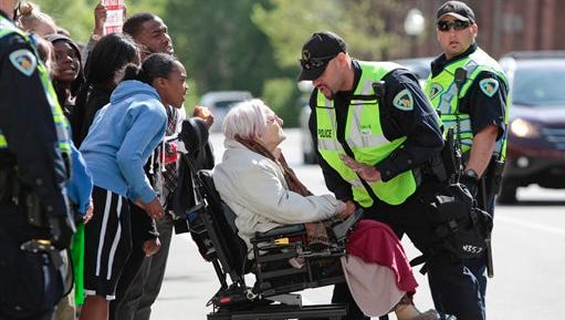 Former Alder, Barbara Vedder is stopped by a police officer from crossing Doty Street during a protest in Madison, Wis., Wednesday, May 13, 2015. Dane County District Attorney Ismael Ozanne announced Tuesday that Madison police officer Matt Kenny would not face charges for the shooting death of unarmed Tony Robinson in March. (M.P. King/Wisconsin State Journal via AP)