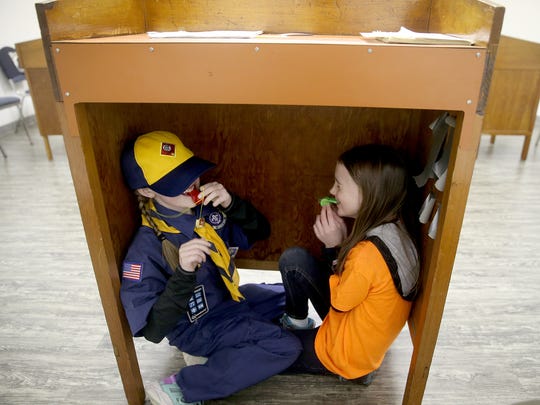 Brianna Richie, 8, and Annabeth Taylor, 7, hide under a podium and blow whistles during a lost hiker drill.