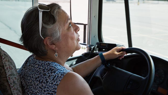 Las Cruces Board of Education President Maria A. Flores drives a school bus and looks up at rear view mirror viewing her rowdy passengers simulated by a few Las Cruces public school bus drivers, August 11, 2016, during the first annual School Bus Driver Job Fair hosted by Las Cruces Public Schools and STS of NM.