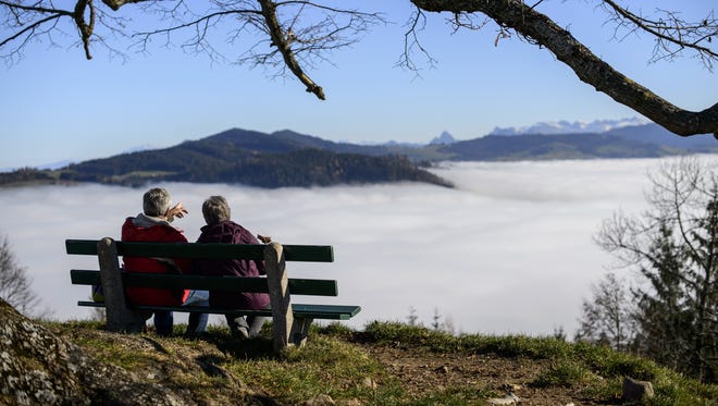 A senior couple sit on a bench above fog hanging in the valley of Hochwacht mountain above Zug in central Switzerland on Nov. 20, 2012.