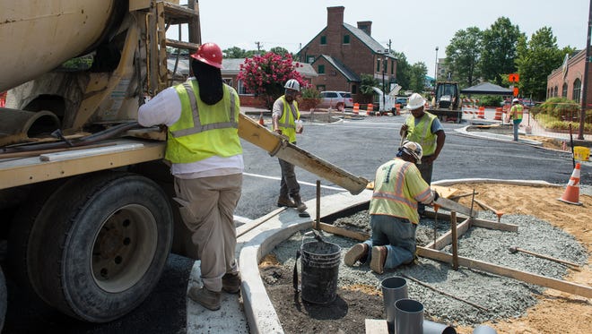 A construction crew work to pour concrete on a sidewalk at the corner of Poplar Hill Avenue and East Main Street in Salisbury on Friday, July 21, 2017. 