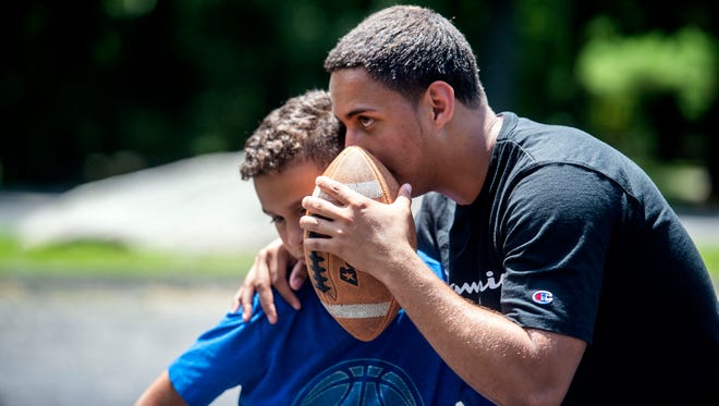 Jordan Bowie, right, whispers a play to Rafael Rodriguez during a game of pick-up football on Thursday, June 28, 2018. Jordan Bowie, a 2017 Central York grad, spent the afternoon playing football with kids during his first year working with the St. Matthew Lutheran Church summer camp program at Rocky Ridge Park. 