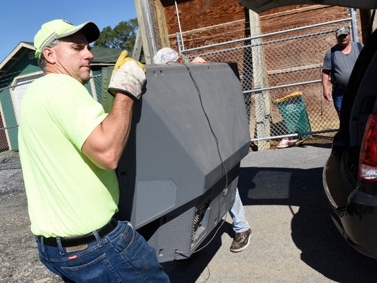 Mark Holtry carries a discarded TV during electronics