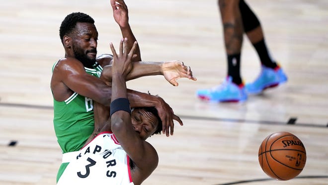 Boston Celtics guard Kemba Walker (left) collides with a Toronto Raptors player while competing for possession during the first half of an NBA basketball game Friday in Lake Buena Vista, Fla.