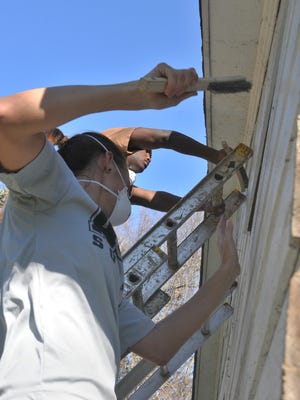 Maren Heller, a member of the AUM soccer team, foreground, scrapes old paint off the back wall of a house on Oak Street. As part of the Martin Luther King Jr. Day of Service, dozens of volunteers help renovate two homes on Oak Street in Montgomery through the House to House nonprofit on Monday, Jan. 19, 2015.