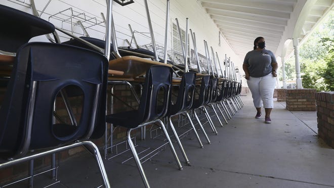 Kristina Washington, special education staff member at Desert Heights Preparatory Academy, walks past a series of desks and chairs at the school Monday, June 1, 2020, in Phoenix, returning to her classroom for only the second time since the coronavirus outbreak closed schools.  Arizona Superintendent of Public Instruction Kathy Hoffman released guidelines on Monday for reopening the state's K-12 schools in August.