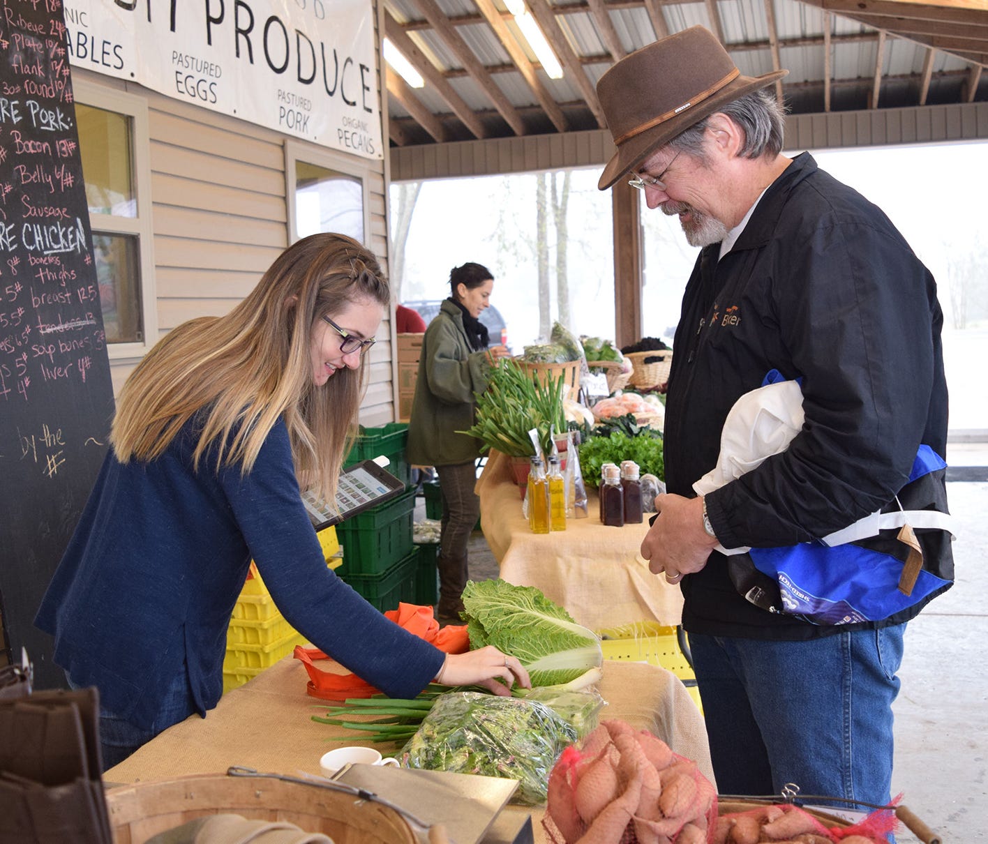 Carmen Buswell rings up produce for Robert Zoehfeld at the Inglewood Farm Saturday market in Alexandria, La. Inglewood Farm uses the Louisiana Grown logo on its website and farmers market displays.