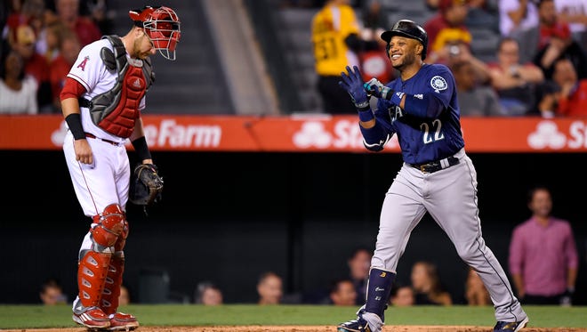 Seattle Mariners' Robinson Cano, right, celebrates after hitting a solo home run as Los Angeles Angels catcher Jett Bandy stand at the plate during the third inning of a baseball game, Monday, Sept. 12, 2016, in Anaheim, Calif.
