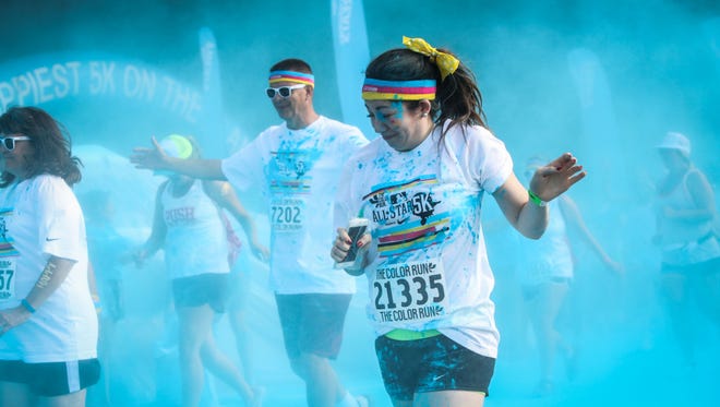 Passing runners are covered in blue powder at the first color station during the 2015 MLB All-Star 5k Color Run.