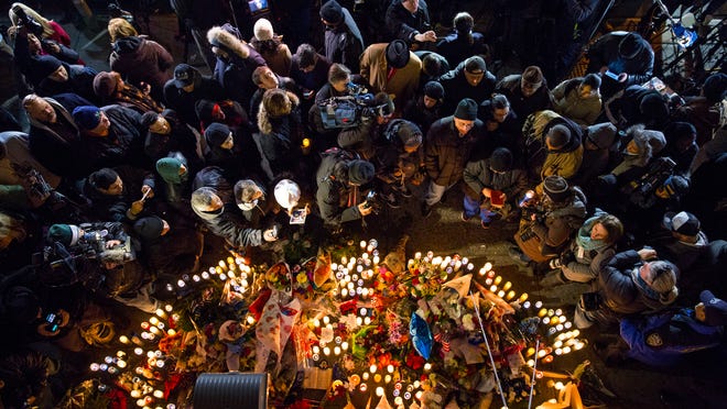 People surround a memorial on Dec. 21 near the spot where two New York Police Department officers, sitting inside a patrol car the previous day, were shot by an armed man, killing them both. The assailant then went into a nearby subway station and committed suicide, police said.
