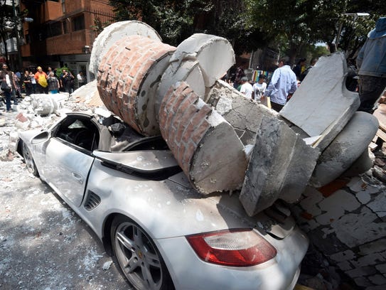 A car crashed by debris from a damaged building after