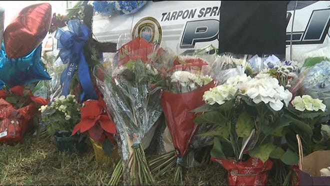 Flowers surround a patrol car Monday, Dec. 22, 2014, outside the Tarpon Springs (Fla.) Police Department in honor of Officer Charles Kondek, who was killed in the line of duty Sunday, Dec. 21, 2014.