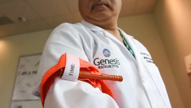 Dr. Stuart Chow, a trauma doctor at Genesis Hospital, looks down at a tourniquet on his arm. He will teach community members how to control bleeding from traumatic injuries in conjunction with National Stop the Bleed Day.