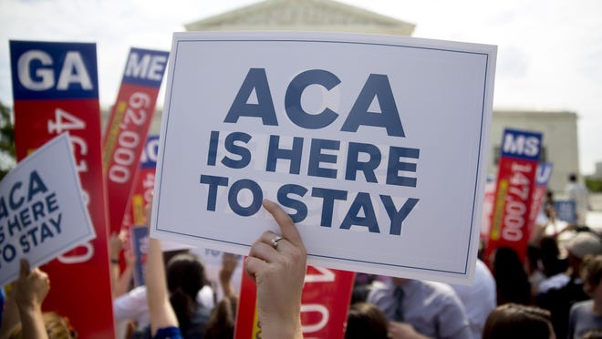 A demonstrator in support of U.S. President Barack Obama's health-care law, the Affordable Care Act (ACA), holds up a "ACA is Here to Stay" sign after the U.S. Supreme Court ruled 6-3 to save Obamacare tax subsidies outside the Supreme Court in Washington, D.C., U.S., on Thursday, June 25, 2015.