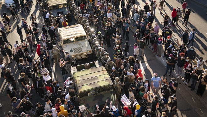 A group of protesters surrounded several National Guard vehicles that were driving on Lake Street towards the blockade under the Hiawatha Light Rail station and forced them to reverse out in Minneapolis on Friday, May 29, 2020.
