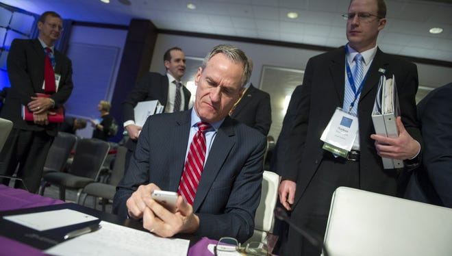 South Dakota Gov. Dennis Daugaard checks his cell phone at the conclusion of the opening session of the National Governors Association Winter Meeting in Washington, Saturday, Feb. 20, 2016.