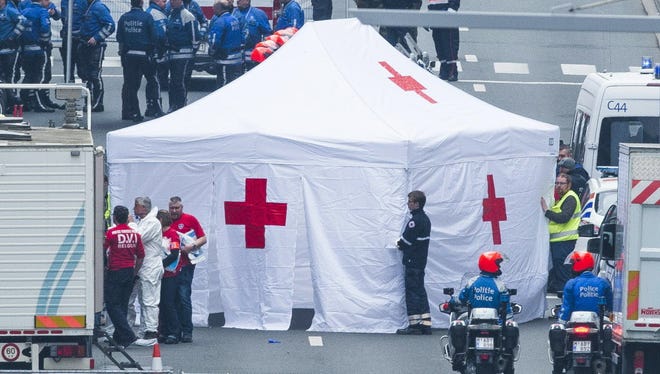 Rescue workers and police officers around a Red Cross tent at the Wetstraat - Rue de la Loi, which was evacuated March 22, 2016, after an explosion at the Maelbeek - Maalbeek subway station in Brussels.